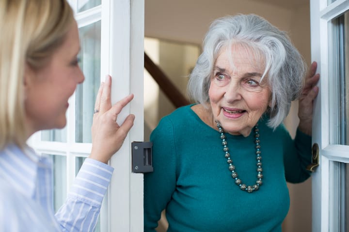 Older lady greeting a visitor by her front door with a smile
